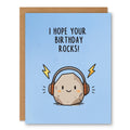 I Hope Your Birthday Rocks Card showing a smiling rock wearing headphones with lightning bolt accents on a blue background with front cover text: I hope your birthday rocks!