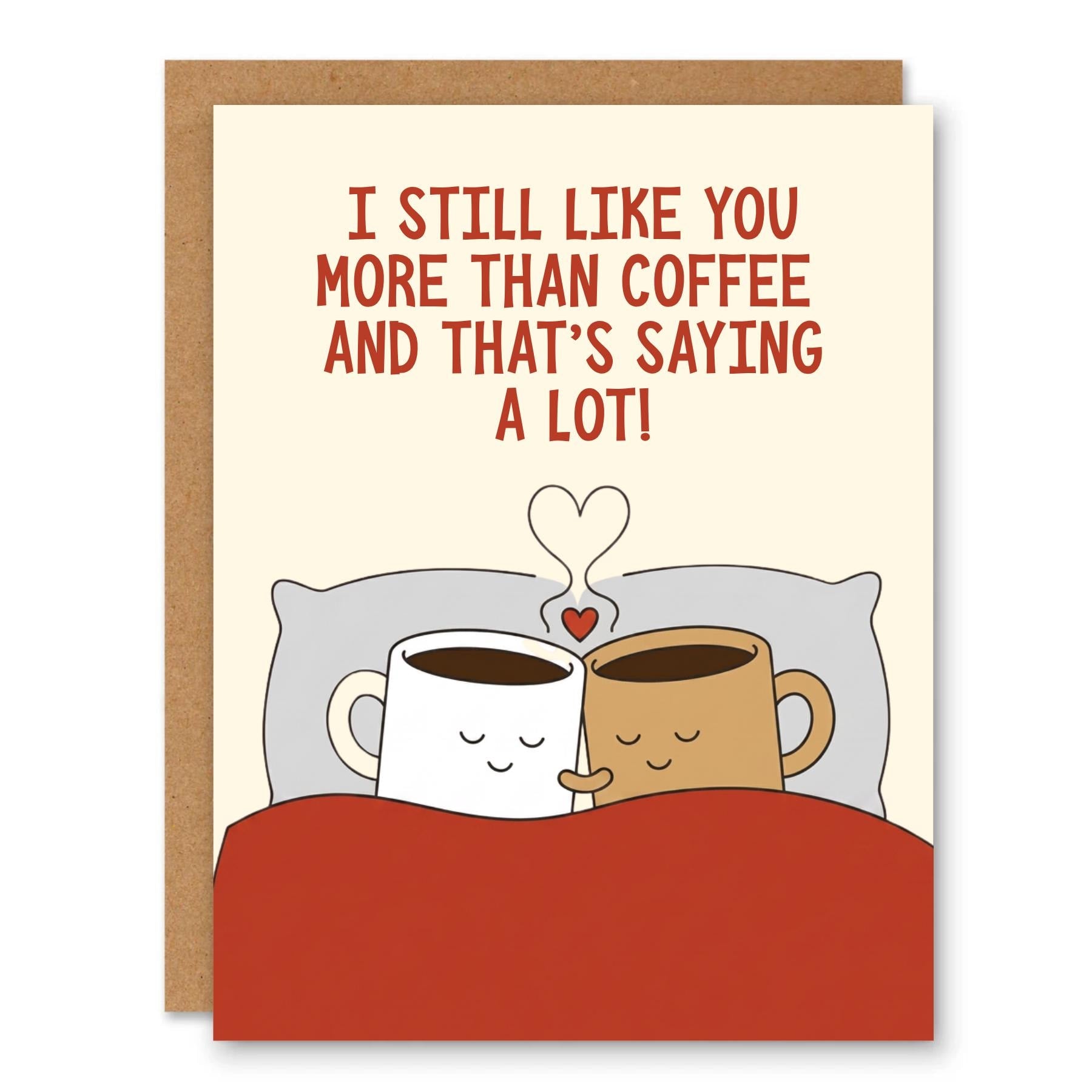 Funny Coffee Love Greeting Card showing two cozy coffee mugs tucked in bed with a heart above them with front cover text: I still like you more than coffee and that’s saying a lot!
